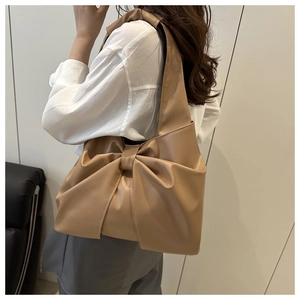 Detail of camel leather tote bag with a large decorative bow and elegant shoulder strap