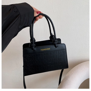 Detail of black faux leather tote with crocodile embossing and golden Fashion Bag text