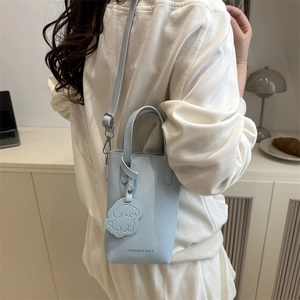 Minimalist light blue mobile phone crossbody bag with a cute puppy charm shown on model