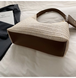 Detail of a woven straw tote bag with brown leather handles and a matching pouch