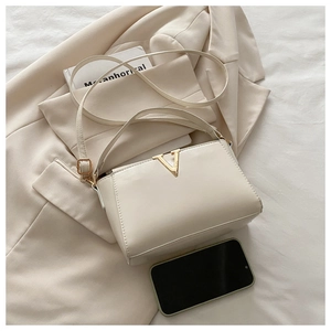 Mini sac à main en cuir ivoire avec fermoir doré en V montré pour détail de la taille