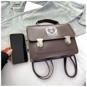 Close-up of brown vintage satchel bag with embroidered crest and dual metal buckles