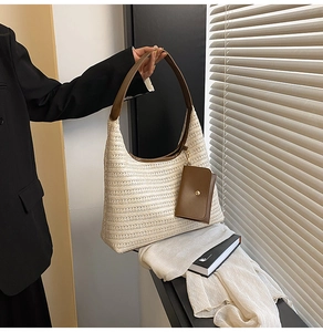 Detail of hand-woven straw tote with leather handle and mini pouch charm in natural light