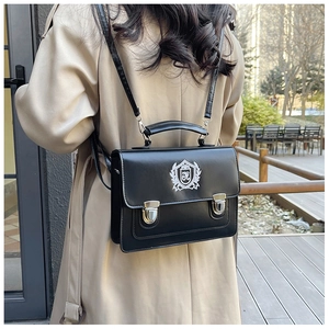 Detail of black vintage satchel bag featuring silver buckles and embroidered shield crest