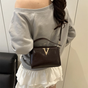 Sac bandoulière marron foncé avec boucle dorée en V vue sous un angle de 45 degrés