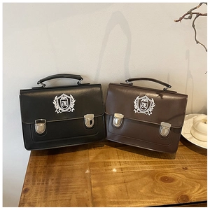 Detail of vintage academy style messenger bags in black and coffee brown with crest