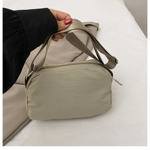 Detail of khaki nylon crossbody bag showing the zipper closure and adjustable strap