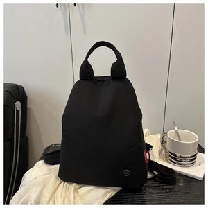 Detail of black minimalist nylon backpack with side red fashion label and metal logo