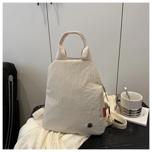 Detail of off-white pleated fabric backpack with red fashion tag and durable nylon handle