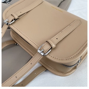 Close-up of beige faux leather tote bag showing fine stitching and gold brand lettering