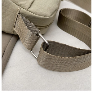 Detail of khaki nylon bag showing the metallic D-ring and woven shoulder strap