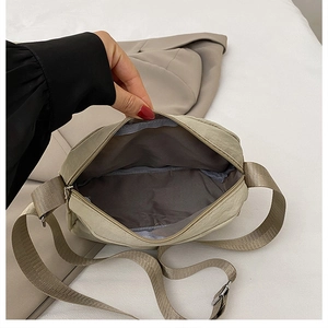 Detail view of the wide woven shoulder strap and metal buckle on the light green tote bag
