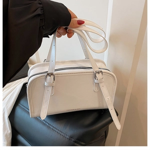 Detail of white leather tote bag featuring black zipper closure and fashion text