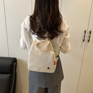Minimalist beige canvas backpack with side fashion tag shown on model in modern setting