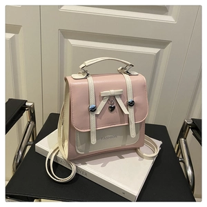 Detail shot of a bow decoration and heart charm on a pink and white backpack
