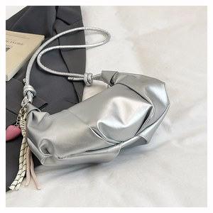 Close-up of metallic silver dumpling bag with heart pendant and knot strap detail