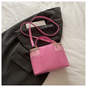 Detail of pink box bag with cherry prints, gold zipper, and adjustable strap on a blazer
