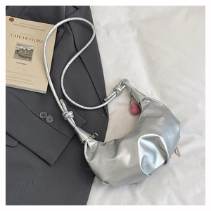 Detail of silver crescent bag with pleated texture and pink heart charm accessory