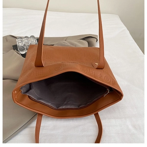 Détail d'un grand sac cabas marron avec gaufrage géométrique et doublure intérieure grise