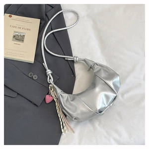 Detailed view of silver metallic crescent bag with pink heart charm and tassel detail