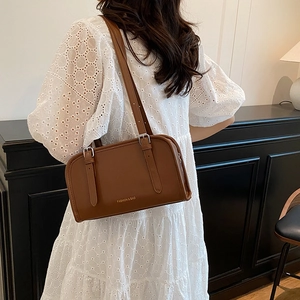 Brown leather tote bag for women showing a retro shoulder strap and minimalist design
