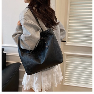 Détail du sac cabas noir avec texture géométrique gaufrée et fines bandoulières élégantes