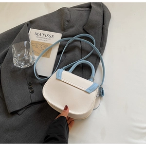 Detail of saddle bag with lychee grain leather, cream body and sky blue trim stitching
