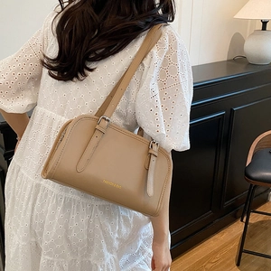 Chic khaki leather tote bag with gold lettering shown in a minimalist interior setting