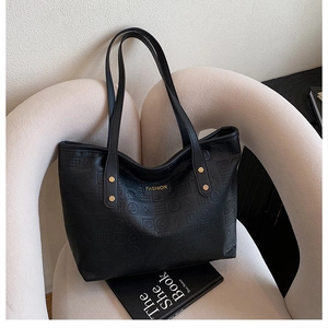 Détail du grand sac cabas noir avec motifs gaufrés et plaque métallique dorée fashion