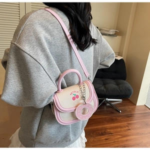 Detail of pink and white cherry saddle bag with donut charm shown on model back