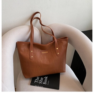 Détail d'un grand sac cabas marron avec gaufrage géométrique et plaque en métal doré fashion
