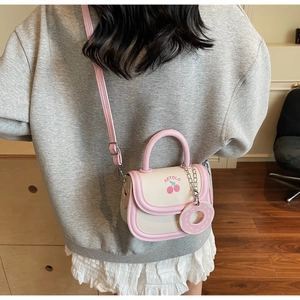 Détail du sac bandoulière rose et beige avec motif cerise et breloque en forme de donut