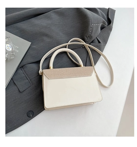 Detail of cream crossbody bag featuring diagonal woven flap and gold-tone hardware