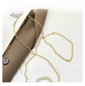 Detail of golden metal chain strap with elegant white pearls on a stylish shoulder bag