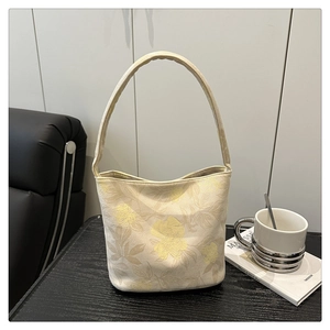 Détail du sac seau crème élégant avec texture jacquard à fleurs jaunes et anse large