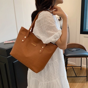Sac cabas marron en cuir gaufré avec plaque dorée et rivets sur la bandoulière d'épaule