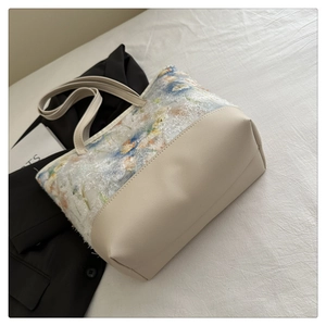Detail of floral tapestry tote bag with cream leather base and structured handle strap