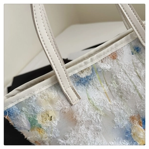 Close-up of jacquard tote bag featuring floral textured fabric and white leather trim