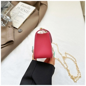 Detail view of pink textured leather crossbody bag with elegant gold chain strap