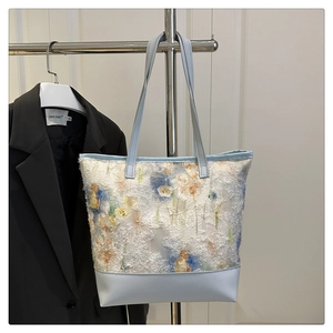 Detail of floral lace tote bag with blue leather base and intricate embroidery