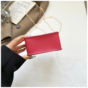 Close-up of fuchsia textured small square bag with fine gold chain and crosshatch leather