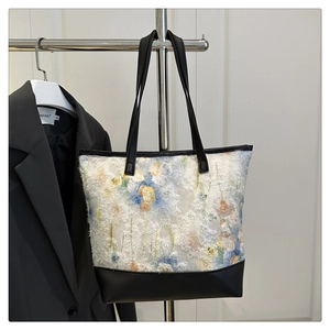 Detailed close-up of large floral tote bag hanging with black leather straps and trim