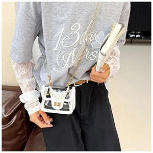 Mini transparent crossbody bag with pearl handle and golden chain shown on a model