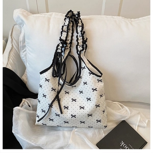 Detail of ruffled shoulder strap with black piping on white polka dot canvas tote bag