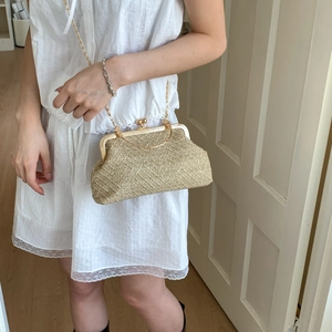Detail of hand-woven straw bag texture with elegant gold metal frame and chain strap
