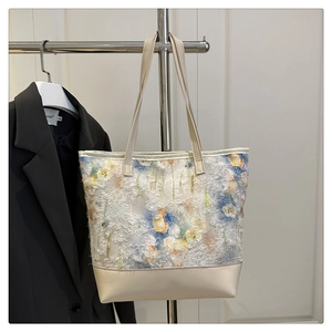 Detailed close-up of colorful floral flocked fabric and beige leather strap on tote bag
