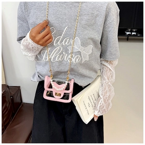 Detail of pink PVC mini crossbody bag with pearl handle and gold chain on model