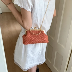 Close-up of rust red woven tweed handbag with gold kiss-lock clasp and chain strap