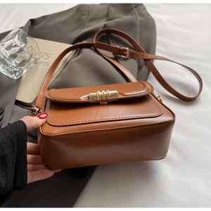 Detailansicht der braunen Ledertasche mit elegantem rechteckigem goldfarbenem Drehverschluss
