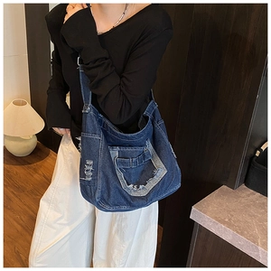 Detail of blue denim tote bag featuring vintage distressed holes and wide shoulder strap